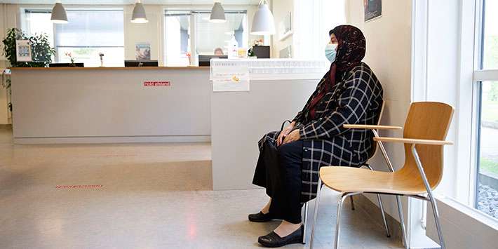 Kvinde med tørklæde sidder i venteværelse