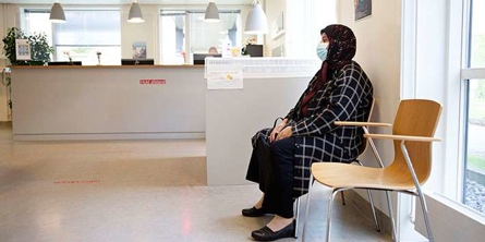 Kvinde med tørklæde sidder i venteværelse