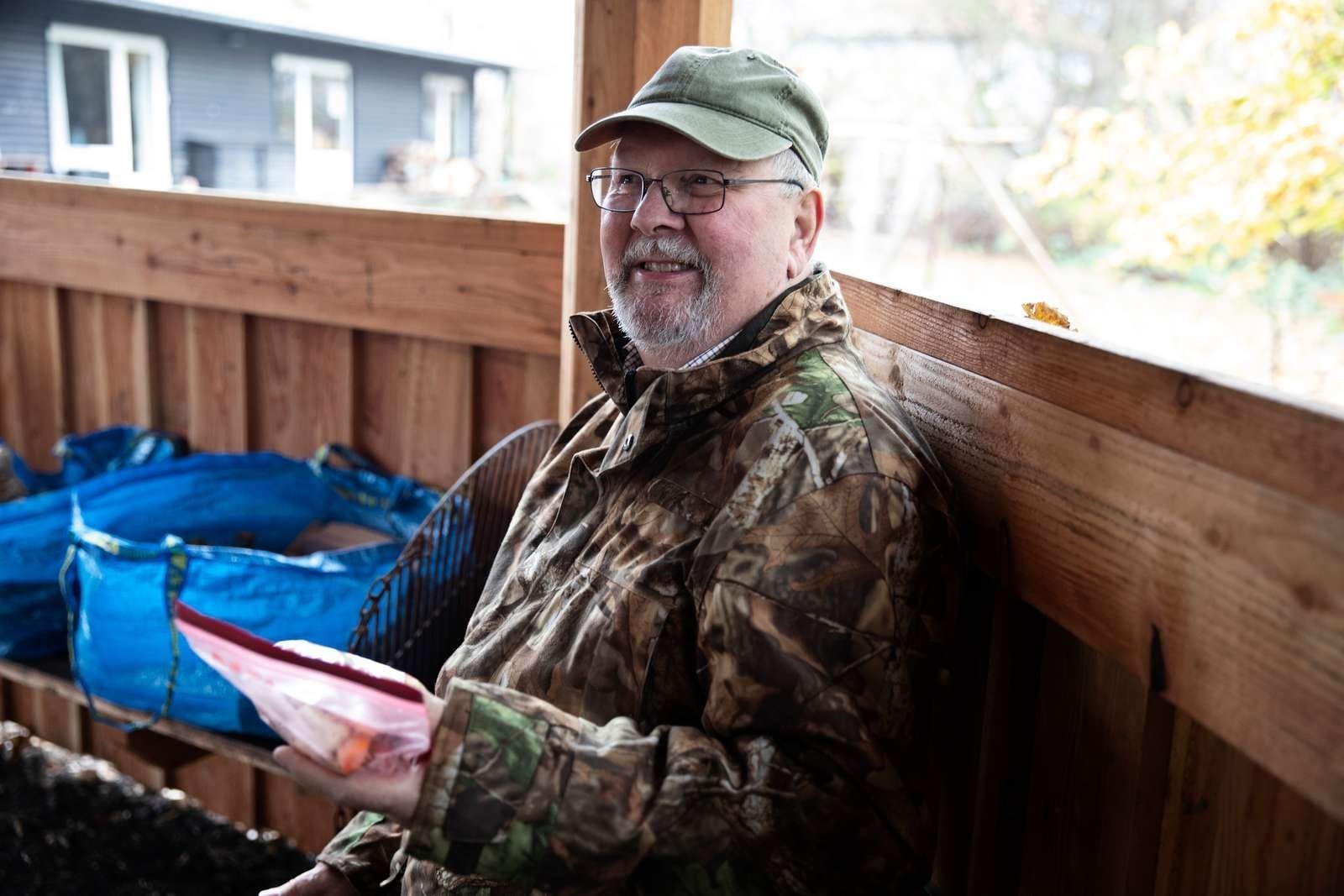 Billede af en ældre mand, der sidder i en shelter med en madpakke i hånden.