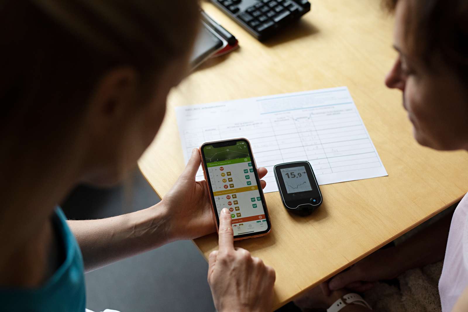 Billede af en app og en aflæser med blodsukkerdata