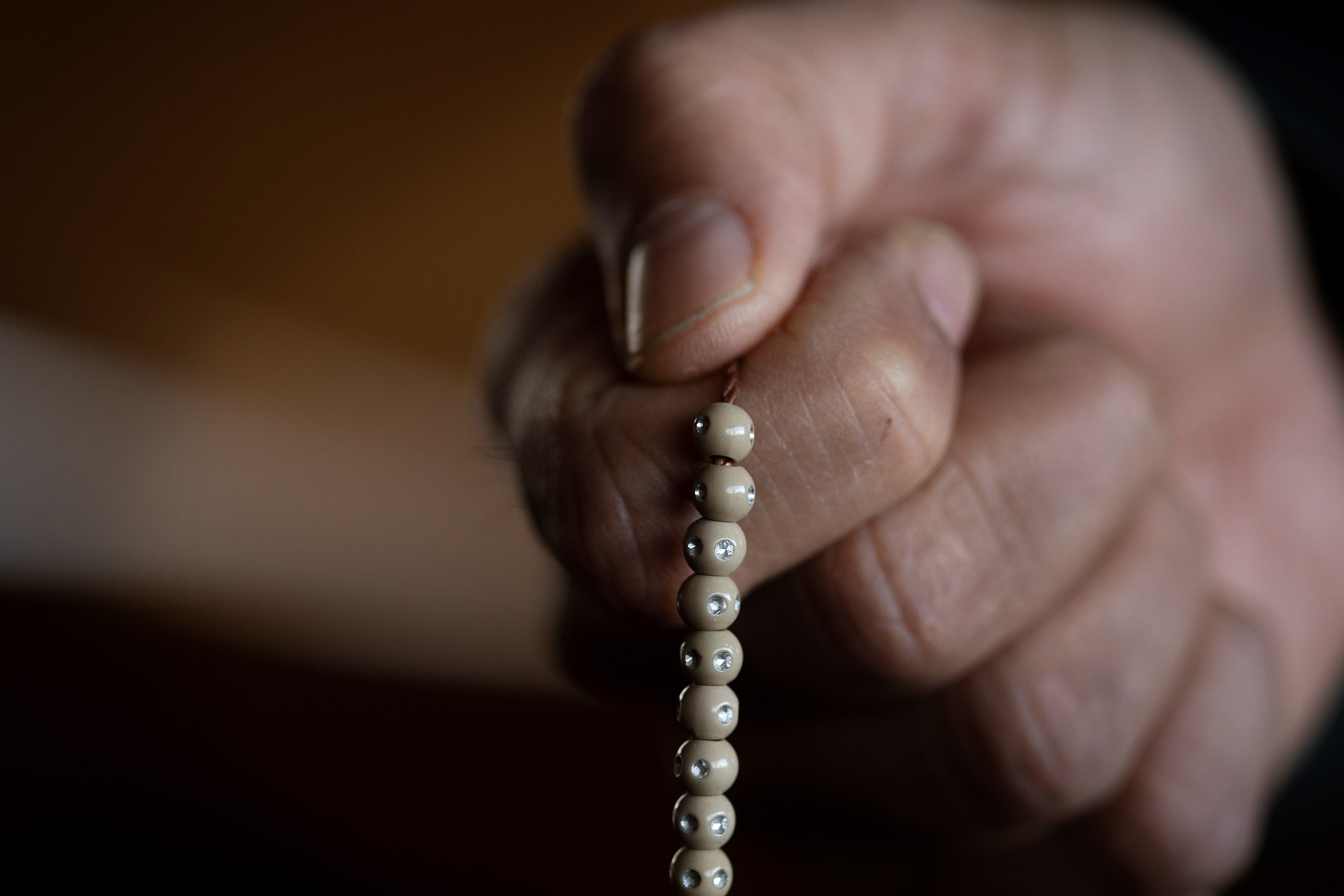 Billede af hånd med bedekrans mellem fingrene