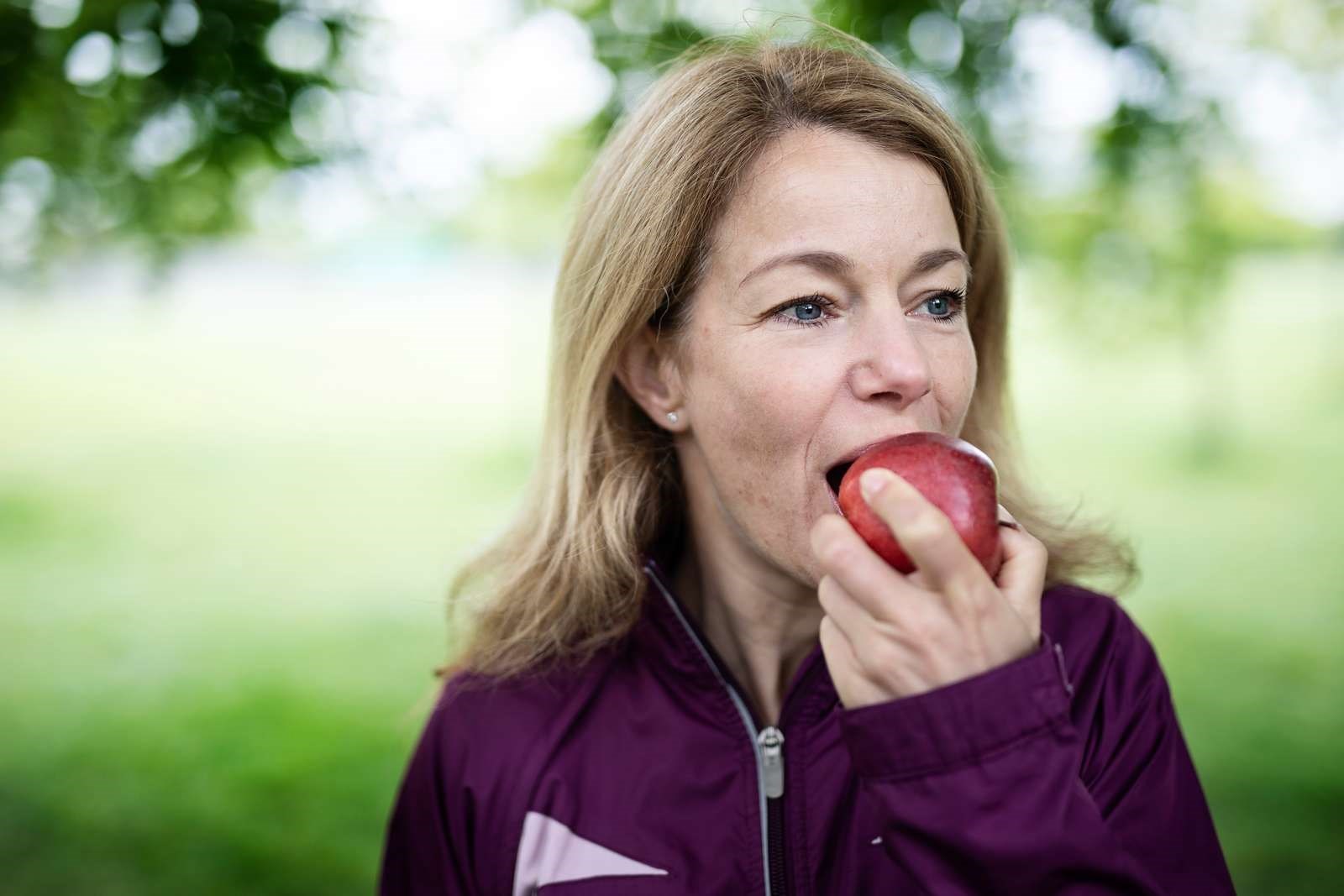 Billede af en kvinde, der spiser et æble. 