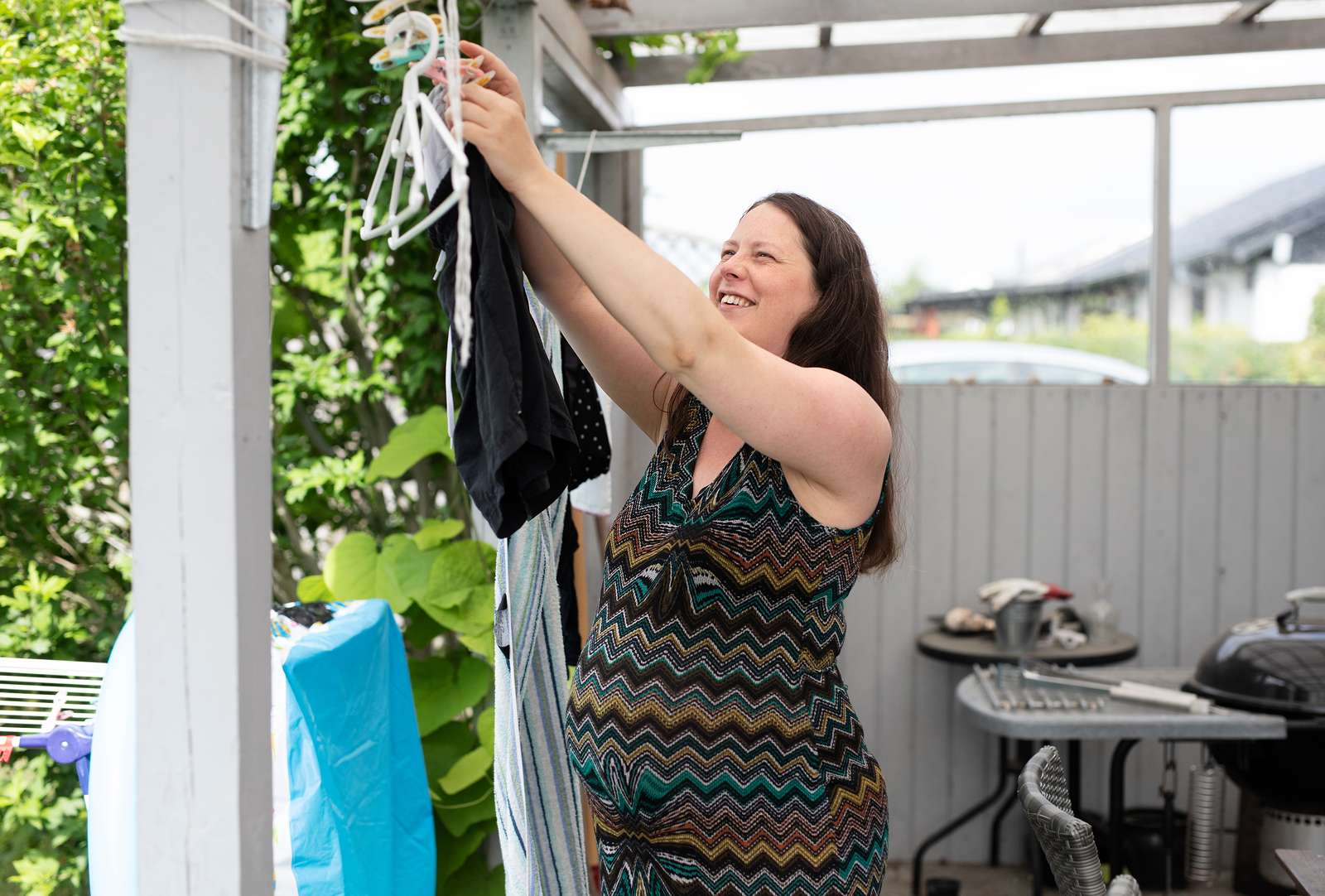 Billede af gravid kvinde, der hænger tøj op.