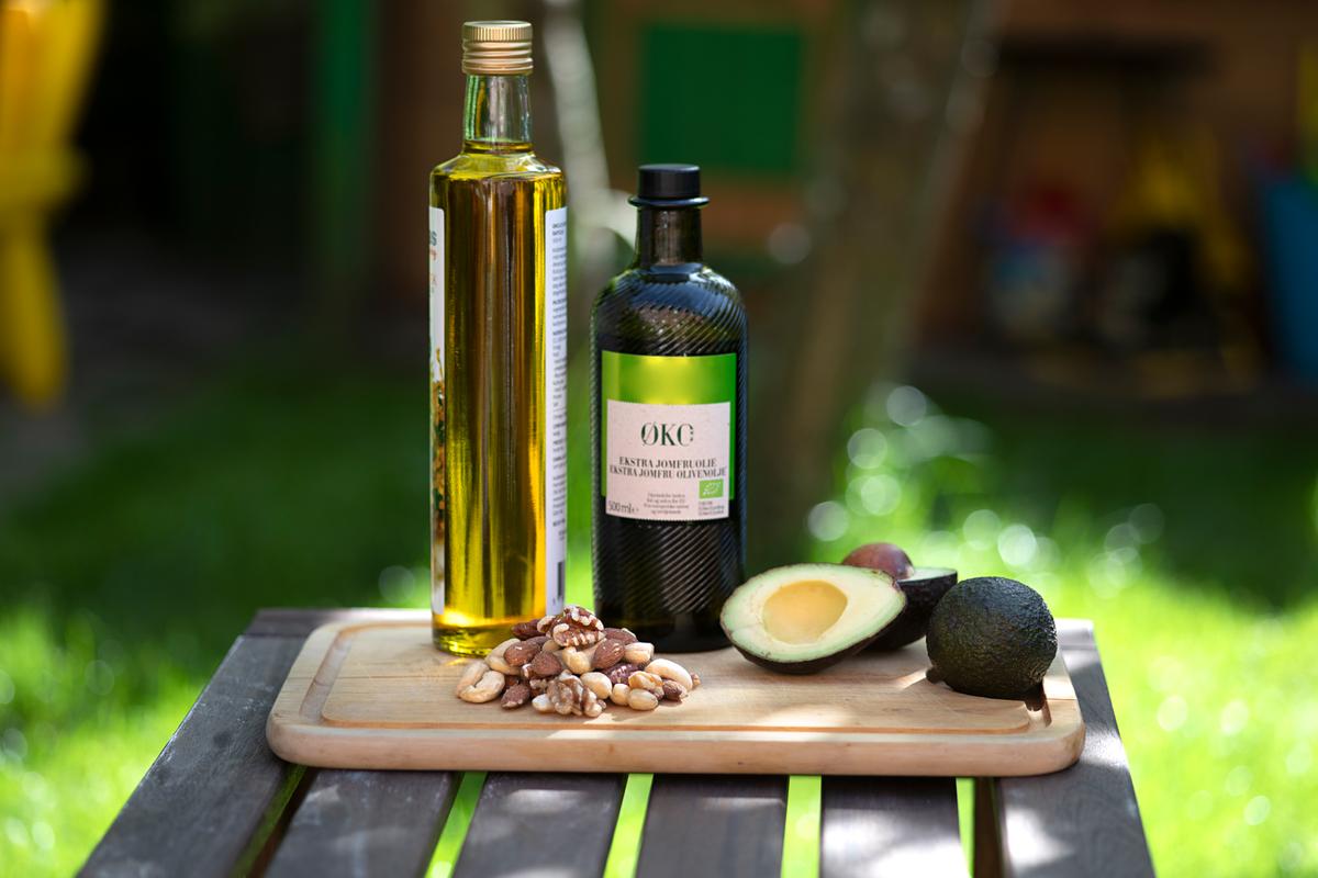 Billede af madolier, avocado og nødder på et skærebræt.