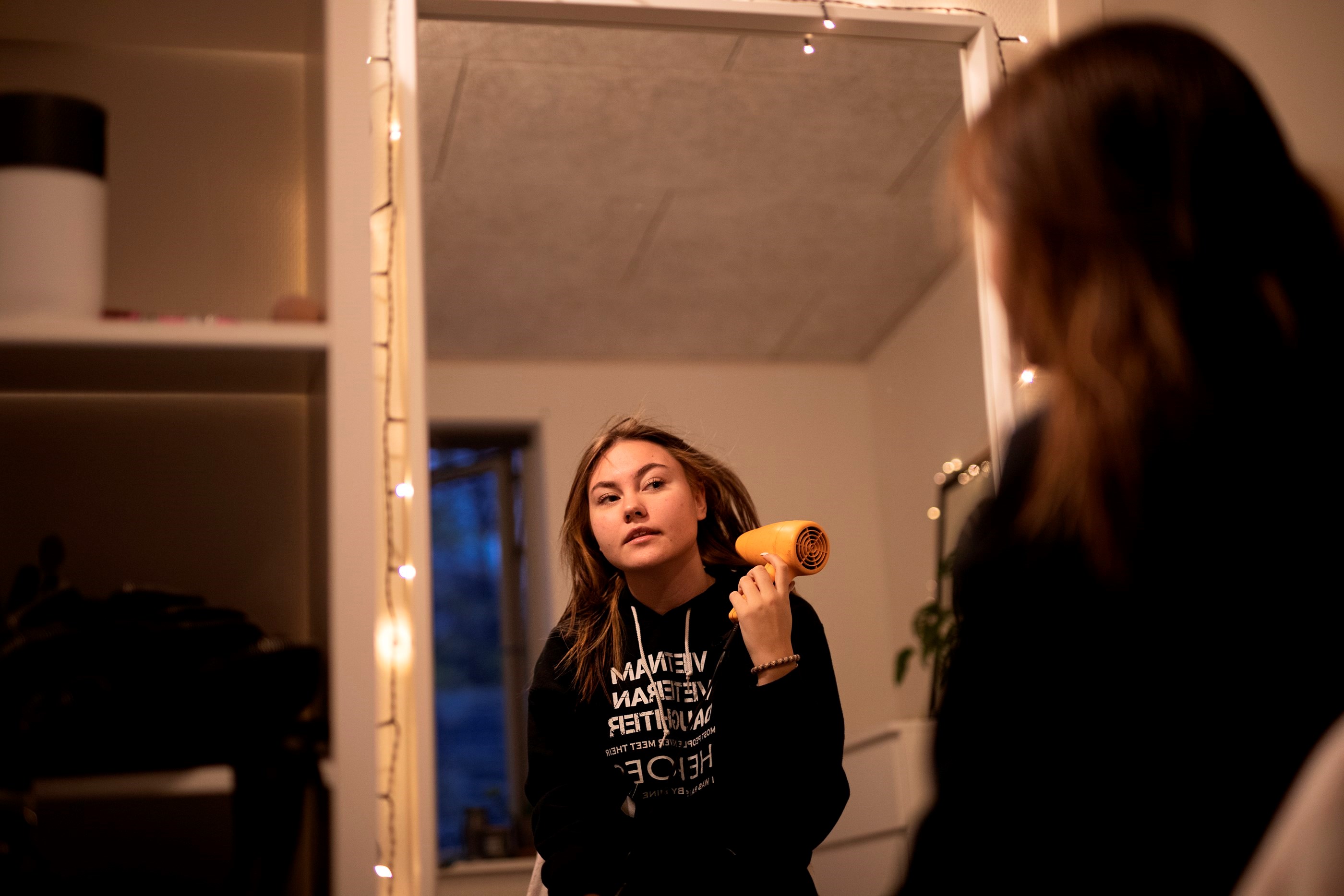 Billede af en ung kvinde med type 1-diabetes, der tørrer sit hår med en hårtørrer foran spejlet.