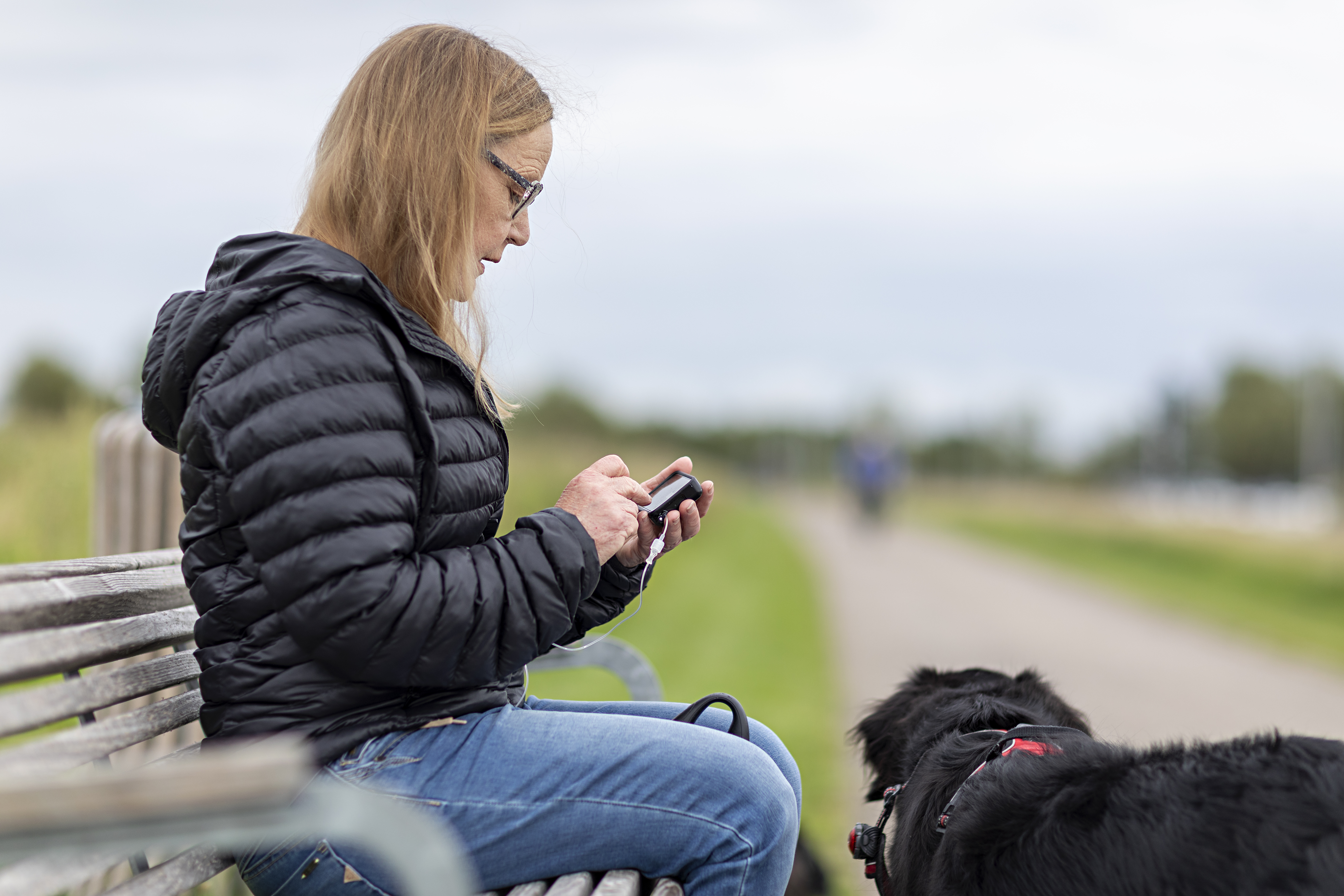 Billede af en kvinde på en bænk i naturen.