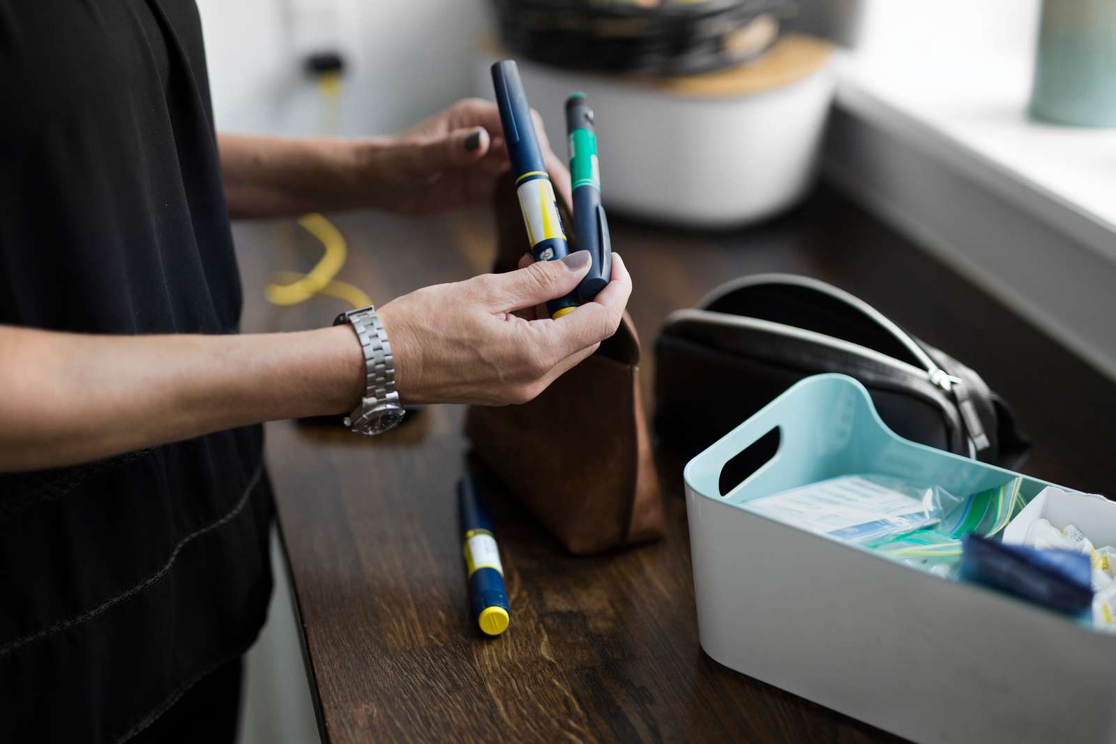 Billede af en kvinde med forskellige insulinpenne i hænderne og en kasse til opbevaring.